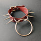 Marsala leather collar with spikes and a metal ring on a gray background