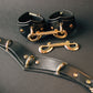 Black leather collar cuffs with gold hardware on a dark background