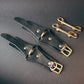 Black leather handcuffs  with gold buckles on a dark gray background