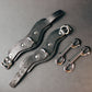 Two leather wrist cuffs with metal hooks on a gray background