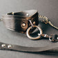 Pair of leather collar with chain leash on a dark surface