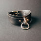 Leather collar with metal ring on a gray background