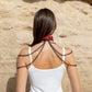 Woman wearing a red leather choker necklaces against a beige stone wall.