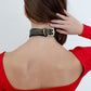 Person wearing a green leather choker with a gold hardware on a plain background
