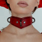 Close-up of a person wearing a red leather choker against a light background