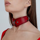 Red leather choker worn by a person against a white background