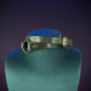 Green leather choker with a gold buckle on a gray background