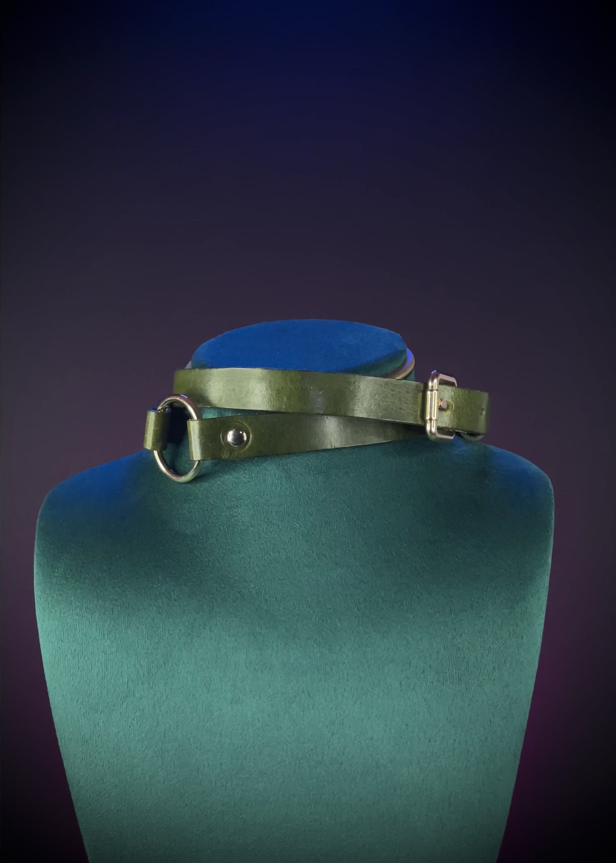 Green leather choker with a gold buckle on a gray background