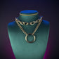 Gold chain necklace with a large ring pendant on a person wearing a black top.