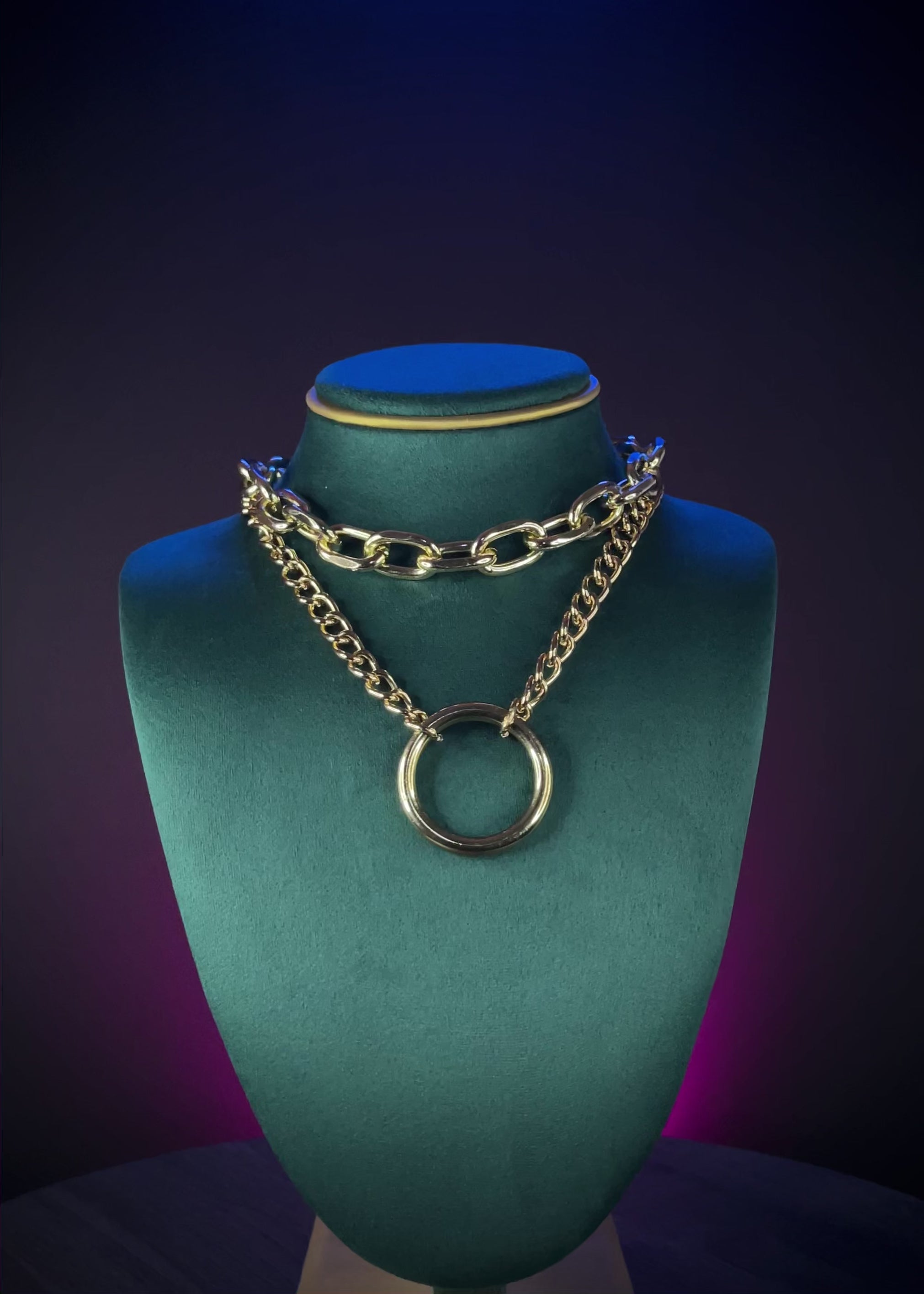 Gold chain necklace with a large ring pendant on a person wearing a black top.