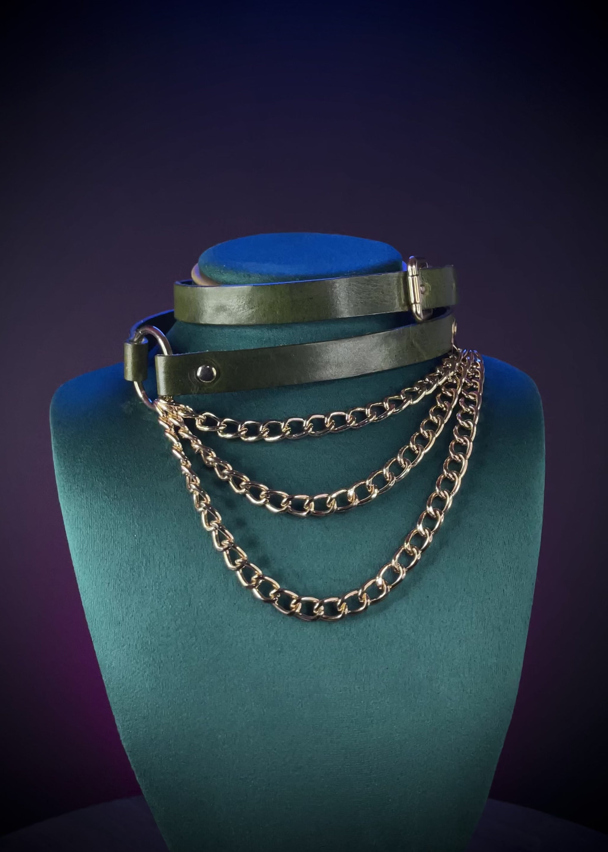 Green leather choker with gold chain and buckle worn by a person
